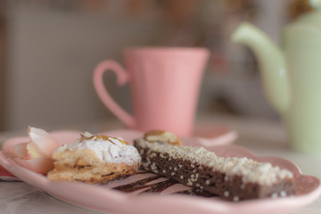 Brunch o desayuno en cafetería rosa, con taza de chocolate caliente, pan dulce y flores rosas en la mesa