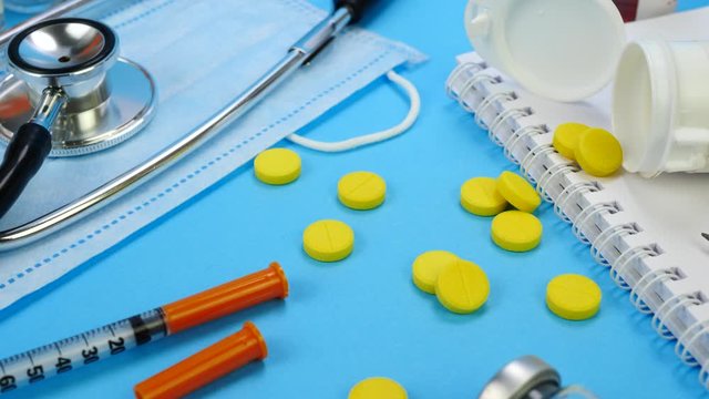 Yellow Medical Pills and Insulin Syringe for Insection near Medicine Tools. Stethoscope and Medical face mask. Paper notebook and Plastic bottle with medicines. Health care and medical concept