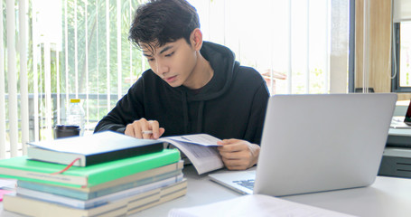 Asian men Students Smile and reading book and using notebook for helps to share ideas in the work and project. And also review the book before the exam