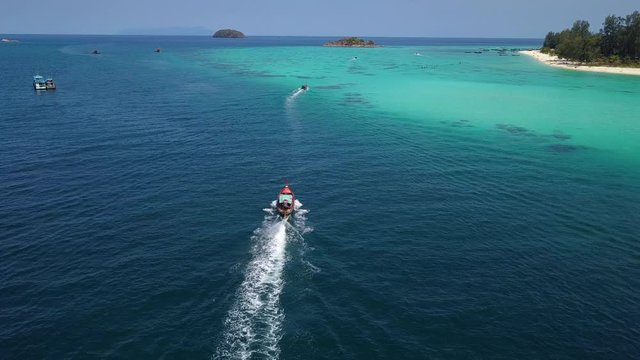 Aerial view of long-tailed boat is sail on the emerald sea. Water traffic with calm andaman sea at Koh Lipe, Satun, Thailand. Dolly motion.