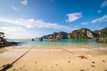 traditional wooden longtail boats parked at a beach in Phi Phi Island. Clear water and clean beach.