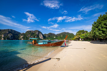 Fototapeta na wymiar traditional wooden longtail boats parked at a beach in Phi Phi Island. Clear water and clean beach.