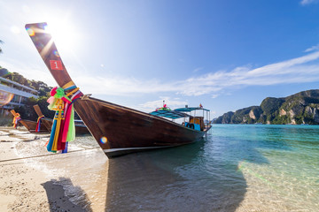 traditional wooden longtail boats parked at a beach in Phi Phi Island. Clear water and clean beach.