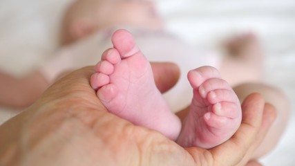 Obraz na płótnie Canvas Newborn Baby Feet In Father Hands. Close-Up.
