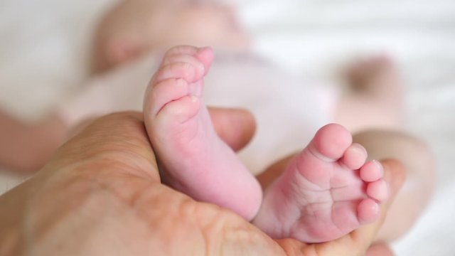 Newborn Baby Feet In Father Hands. Close-Up.