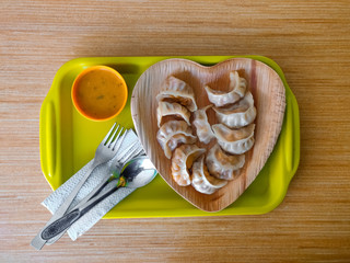 Momo served in a heart-shaped plate placed on a wooden surface.