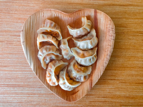 Momo served in a heart-shaped plate placed on a wooden surface.