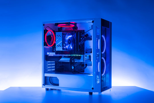 the new modern powerful gaming computer with beautiful rgb lights of different color and a glass case on the table in the dark