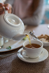 Pouring tea from their porcelain teapot.