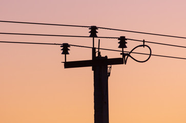 Electric pole with wires on a sunset background