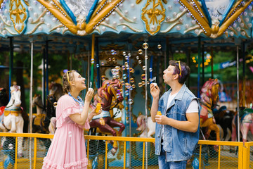couple in love blows soap bubbles at each other, they are happy and laughing in an amusement Park. Valentine's day