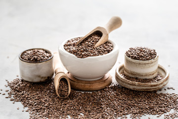 Flax seeds in ceramic bowl isolated with wooden spoon on white background. Organic healthy food