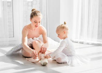 Little girl is taught how to tie ballet pointe shoes