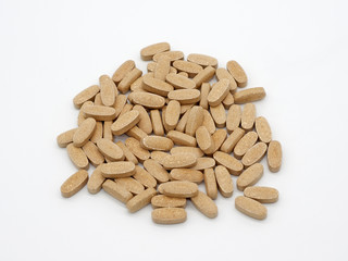 Mountain of big oval pills of gray color on a white background