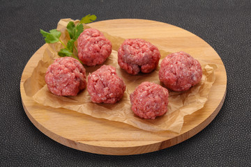 Raw meatball over wooden background