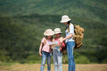 The three siblings watched the map on the street, carrying a backpack and wearing a hat in the...