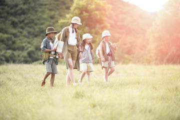 Fototapeta premium Happy asian woman girl and children goes to summer travel trip with mountain background. they checks map to find directions. Smile and enjoying their time together. Travel and adventure concept.