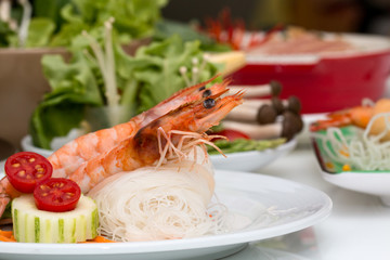 Close up of delicious shrimp on rice noodles in white disk placing together with various ingredient as background