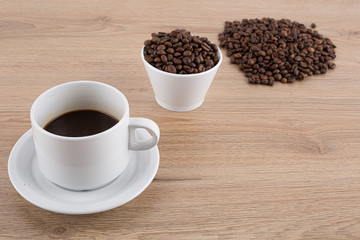 cup of coffee with coffee beans on wooden table and white wall