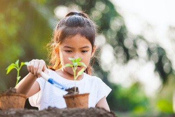 Cute asian child girl planting young tree in recycle fiber pots in the garden with fun