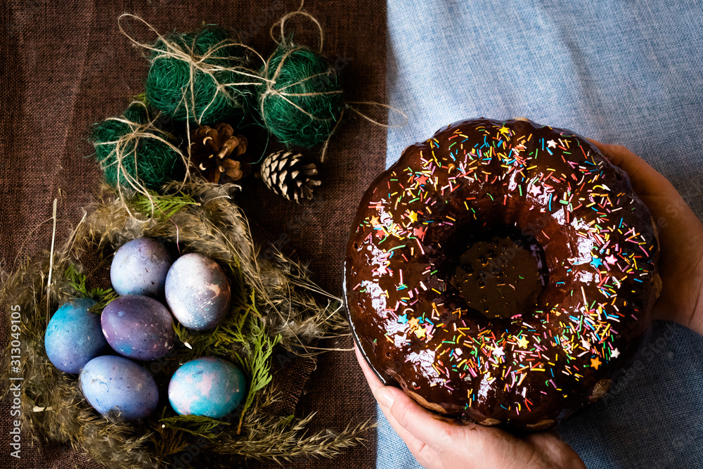 Wall mural woman holding chocolate cake with powder next to space galactic easter eggs in nest next to bump and