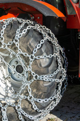 close up of heavy-duty snow chains mountain on tire of small tractor