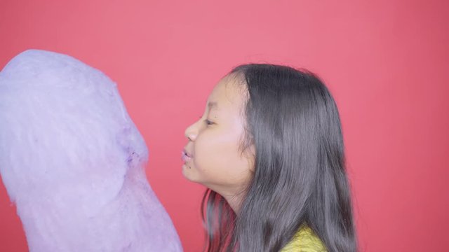 Little girl licking and eating a cotton candy on studio