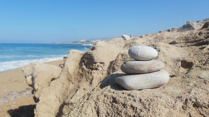 pyramid of white stones on a rocky shore, blue sea, blue sky