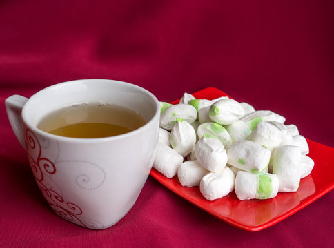 green tea in a white cup and parvarda sweets