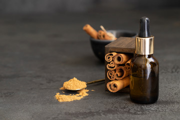 Essential cinnamon oil in glass bottles and cinnamon natural sticks. Aromatherapy and Ayurveda concept.