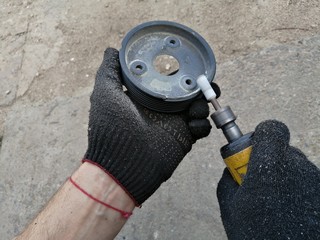 alignment of the edges of the car pulley in the hands of a worker with a pneumatic machine