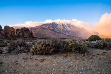 Spain, Tenerife, Blue sky over popular mountain volcano teide with foggy clouds and plants in caldera desert nature landscape in golden sunset light