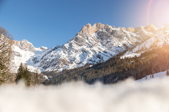 Sunny winter landscape in the nature: Mountain range, snowy trees, sunshine and blue sky