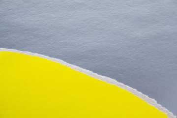 Yellow torn piece of cardboard on silver grey sheet of paper texture background. Can be used for...