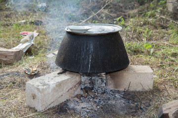Old fashioned cooking stove with metal steel pans on a fire. Cooking food by scout at camping scout...