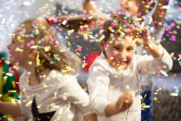 Background party for children. Multicolored confetti on the background of joyful faces.