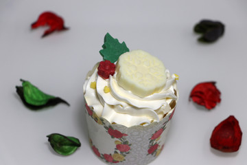 Christmas cupcakes decorated with white chocolate and colorful flower petals on the floor.