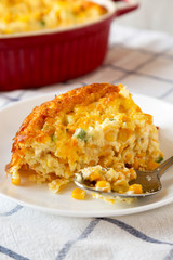 Homemade Cheddar Corn Pudding Casserole on a white plate, side view. Close-up.
