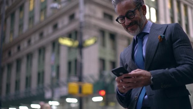 Happy businessman enjoying positive smartphone messaging with best client connected to 4g wireless in group chat, successful man in luxury suit typing email with good news