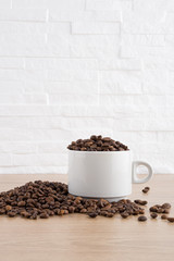 cup of coffee with coffee seeds on wooden table and light brick background
