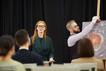 Woman and man preparing for the presentation they are going to present paintings to business people