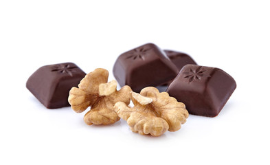 Closeup shot of cut dark chocolate with walnuts on white background.