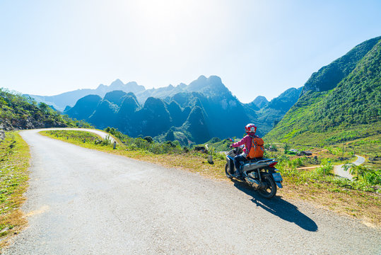One person riding bike on Ha Giang motorbike loop, famous travel destination bikers easy riders. Ha Giang karst geopark mountain landscape in North Vietnam. Winding road in stunning scenery.