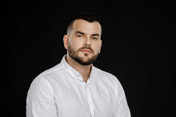 Obraz premium calm handsome bearded man poses in studio on black background