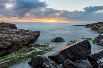 sunrise with waves crashing over the rocks 