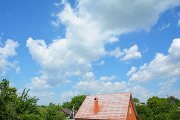 Fototapeta na wymiar Brick house rooftop with steel roof and beautiful clouds blue sky