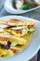 Classic breakfast, hot sandwiches with cheese, vegetables and chicken on a wooden table. Hand-made, rustic breakfast, toast with turkey and vegetables. Soft focus.