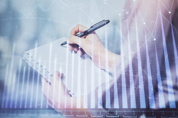 Multi exposure of hands making notes with forex chart huds. Stock market concept.