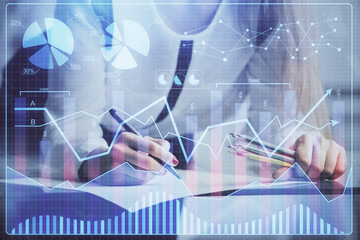 Double exposure of hands making notes with forex chart huds. Stock market concept.