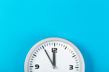 White wall clock with a yellow used hanging on the wall. Minimalist image of a wall clock on a blue background with copy space